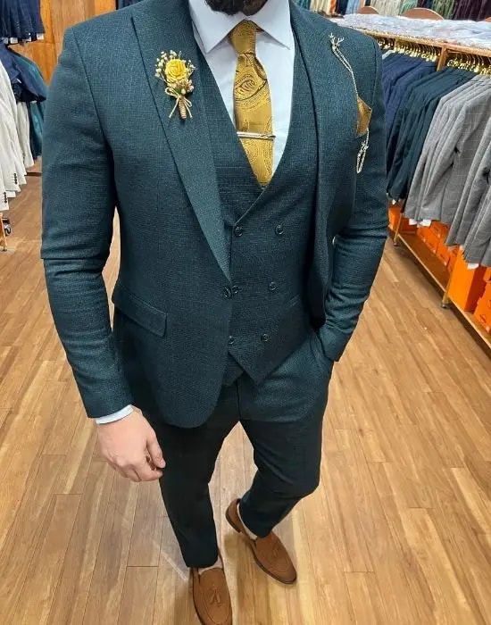 Homme en costume trois pièces vert avec cravate dorée