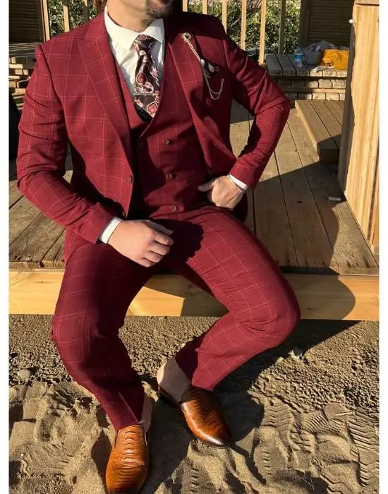 Homme en costume trois-pièces bordeaux assis à l'extérieur