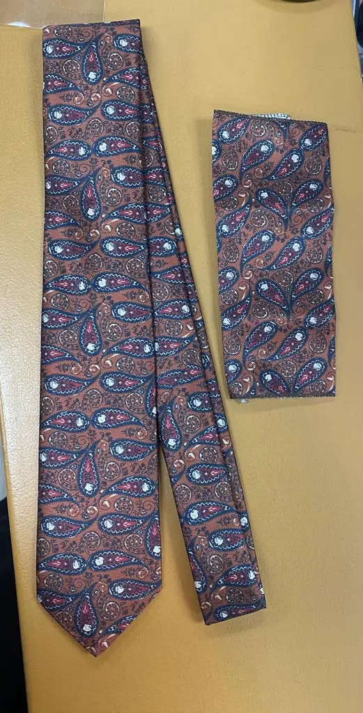 Cravate et pochette à motifs cachemire sur table beige