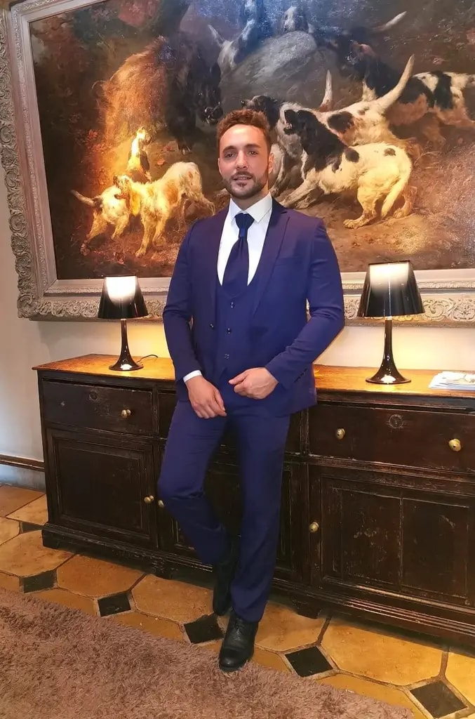 Homme en costume bleu devant un tableau de chiens