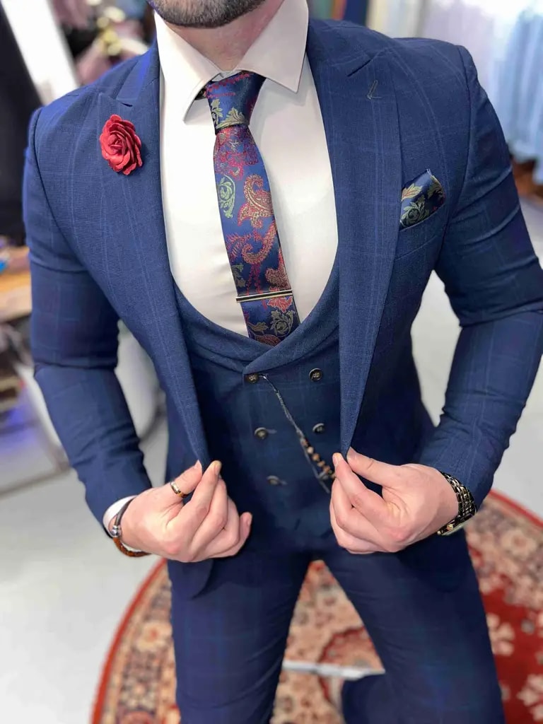 Homme en costume bleu avec cravate à motifs et pochette