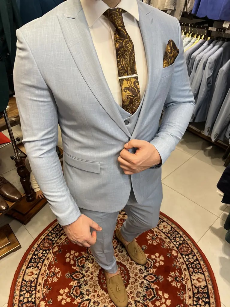 Homme portant un costume bleu clair avec cravate dorée