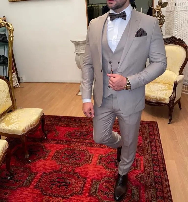 Homme en costume beige élégant avec nœud papillon.