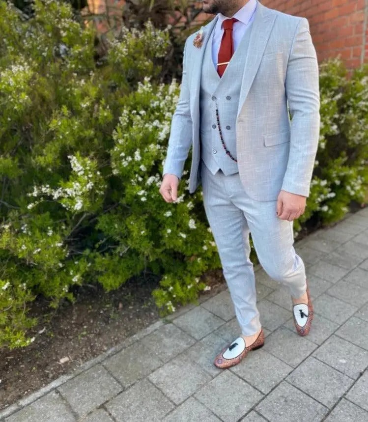 Homme en costume trois pièces gris clair avec cravate rouge