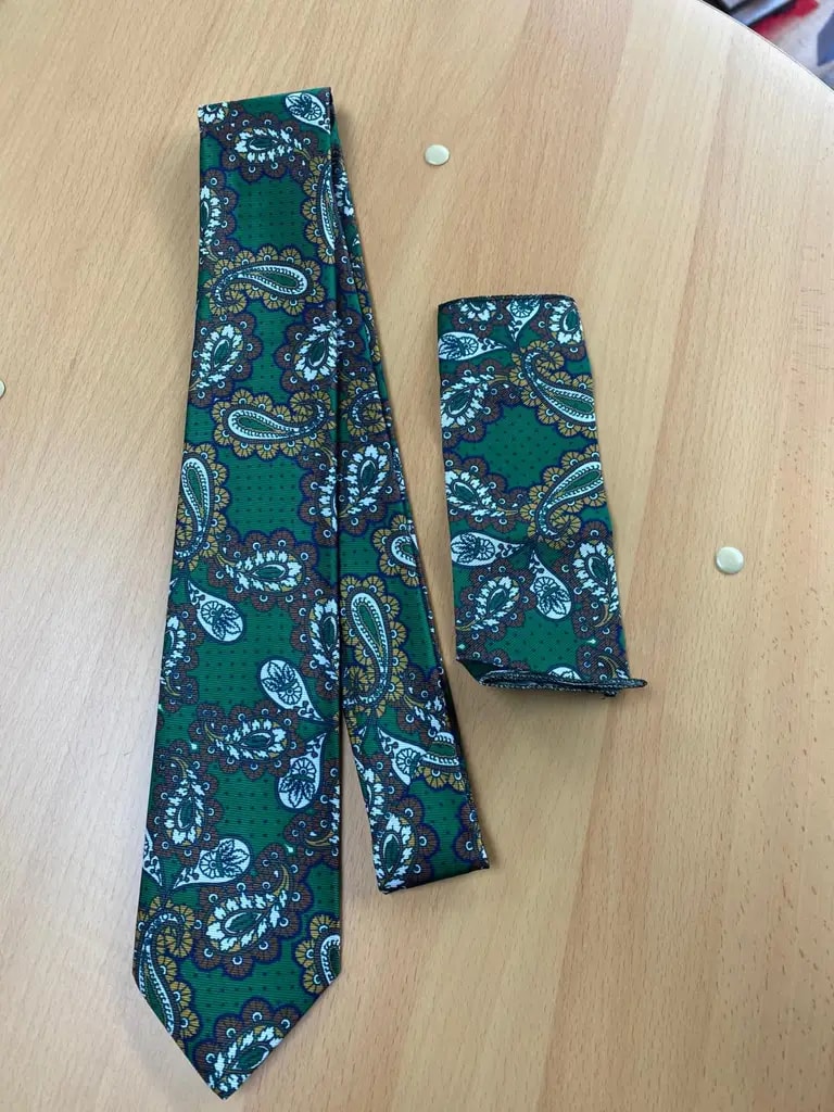 Cravate et pochette vertes à motifs paisley sur table en bois