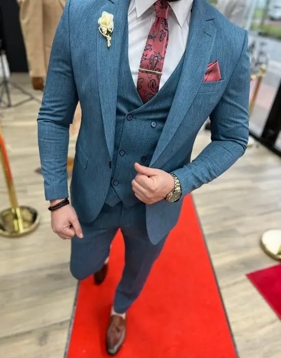 Homme en costume trois pièces bleu sur tapis rouge